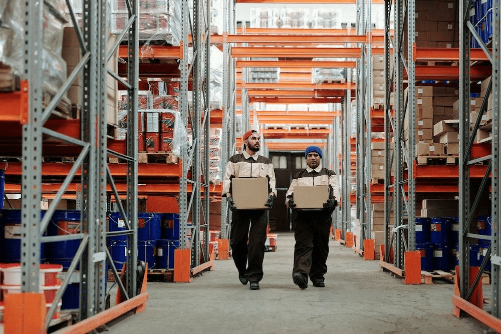 two warehouse workers carrying boxes